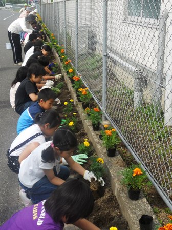 （写真）小学生と一緒に花を植える様子
